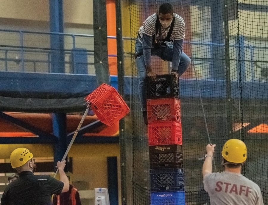 Kylen Lunn balances his body on a tall pile of crates before attempting to add one more crate to the stack during the Crate Stack Challenge held on Tuesday March 16, 2021, at Recreational Center, Carbondale Ill.