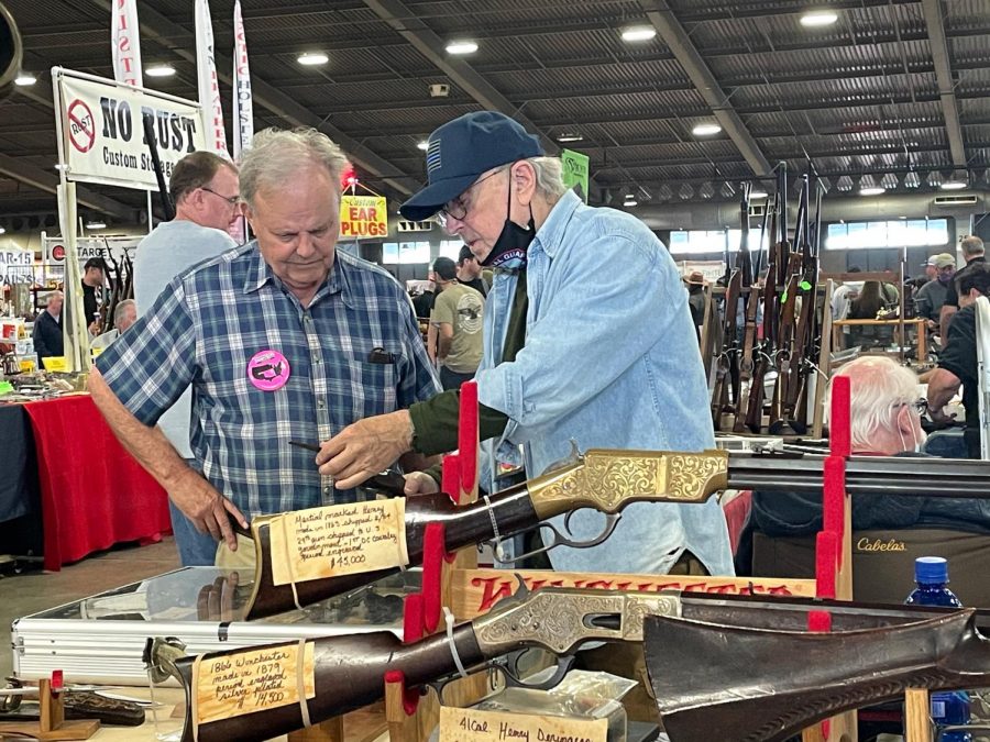 Two gun sellers inspect a revolver at the world’s largest gun show, the Wanenmacher’s Tulsa Arms Show. The show was a two day event and took place on April, 10 and 11, 2021, at Expo Square in Tulsa, Okla. More than 25,000 people participated in  the show. 
