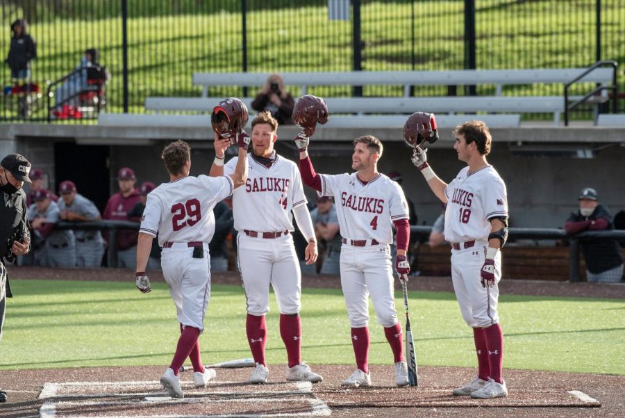 Saluki players Phillip Archer (44) Brad Hudson (4) and Tony Rask (18) congratulate Cody Cleveland (29) after hitting a home run in the second inning during the game against Bellmore on April 10, 2021 at Itchy Jones Stadium in Carbondale, Ill.