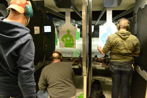 A spectator looks on as Jack B. and Seth M. loaded guns at a shooting range in the Chicago, Ill. suburbs.