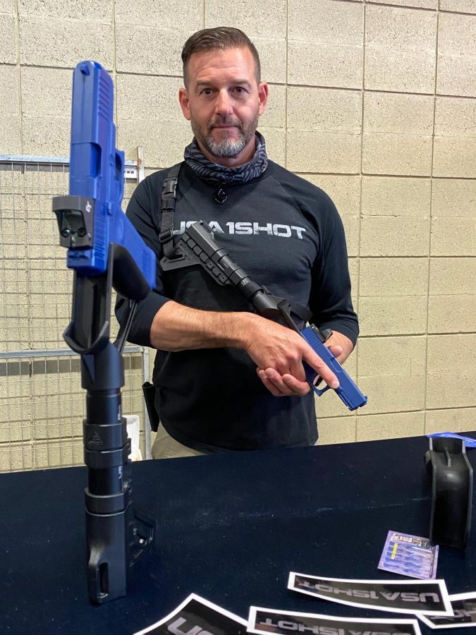 Sawyer, who would only provide his first name, poses for a portrait while demonstrating how to hold a pistol using the adapted stock he created to provide stability at the Wanenmacher’s Tulsa Arms Show on April 10 and 11, 2021, in Tulsa, Okla. 
