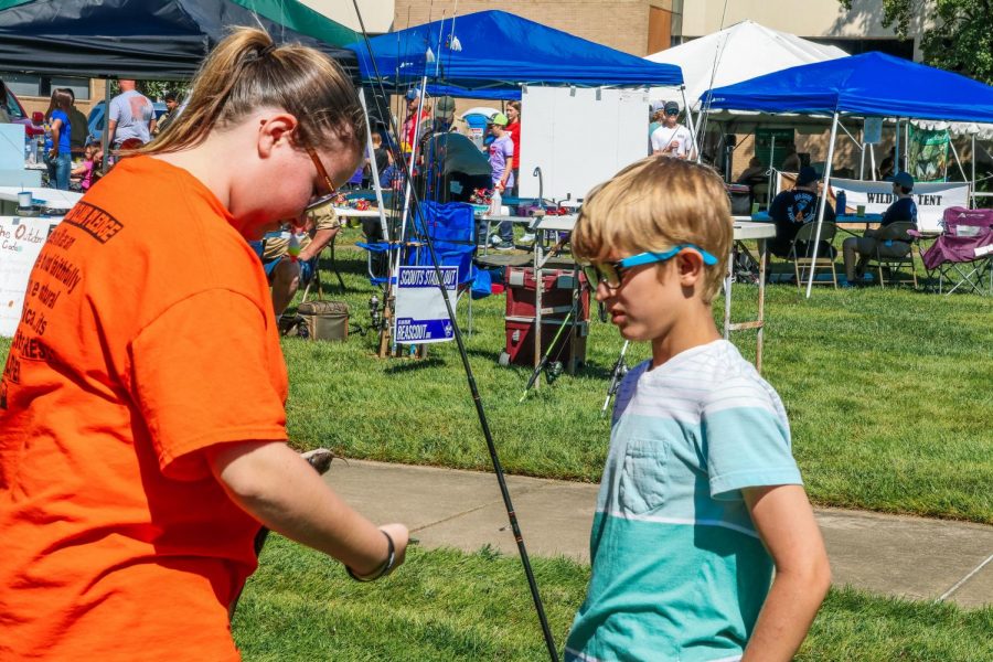 Izzy Wilson, member of the outdoor club, helps kid get hook out of a fish Sept. 26, 2021 at Southern Illinois Hunting and Fishing Days in Carbondale, Ill. This may be the only time to do things as a family like go fishing, so it makes their day catching a fish, Wilson said.