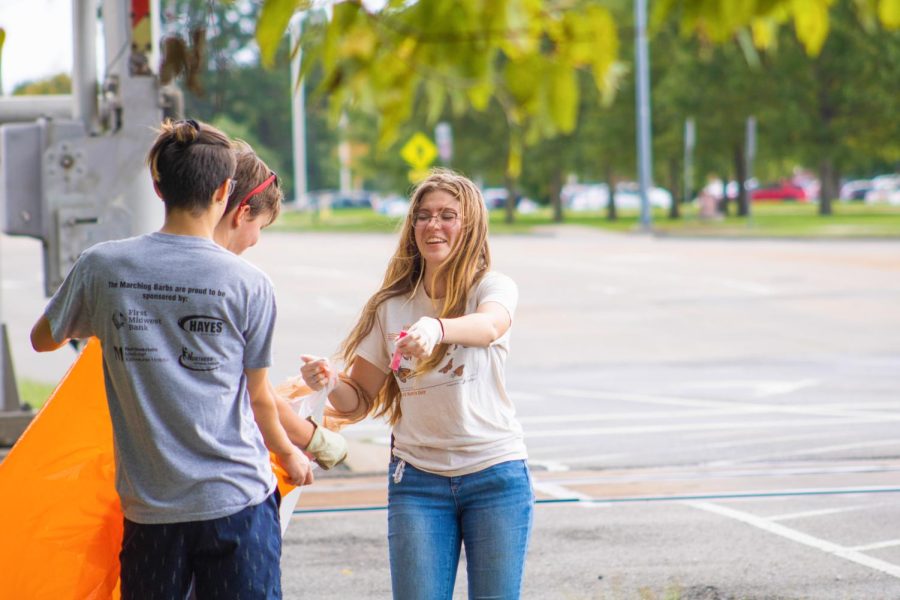 (Pictured left to right) Caleb Hoffman and Leah Kleiman hold open plastic bags for Alex Barnes to toss litter into Oct. 3, 2021 on E Grand Avenue in Carbondale Ill. 
