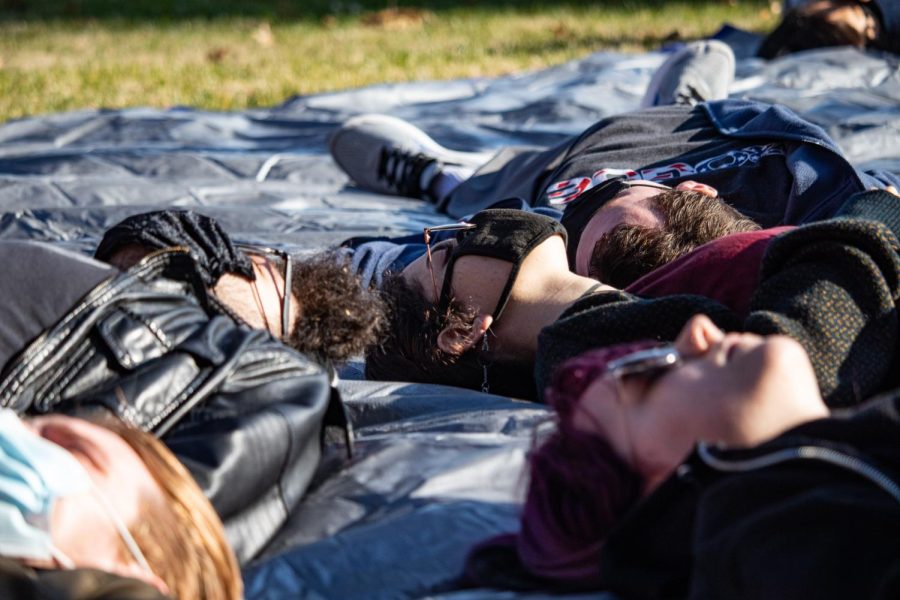 Protestors lie on a tarp during the die-in protest Dec. 1, 2021 in front of Anthony Hall at SIU in Carbondale, Illinois. 
