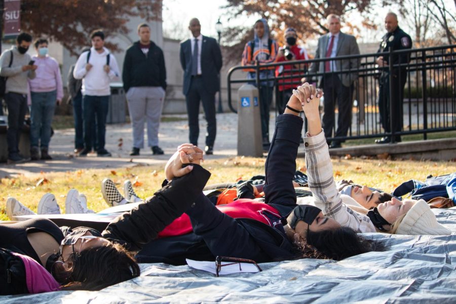 Protestors hold hands during die-in protest in front of Anthony Hall Dec. 1, 2021 at SIU in Carbondale, Illinois. 