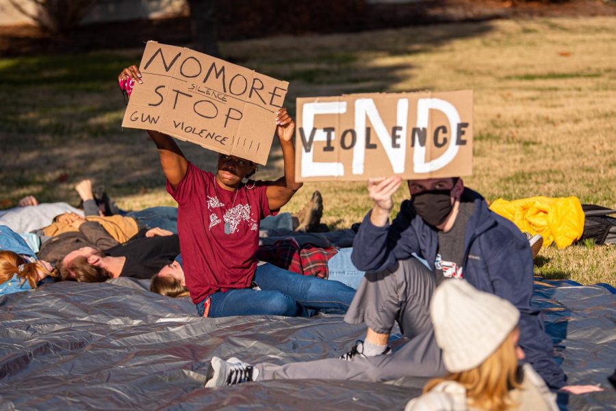 Two protester hold up signs as chancellor Lane addresses the crowd during the die-in protest on Dec. 1, 2021 at SIU. 