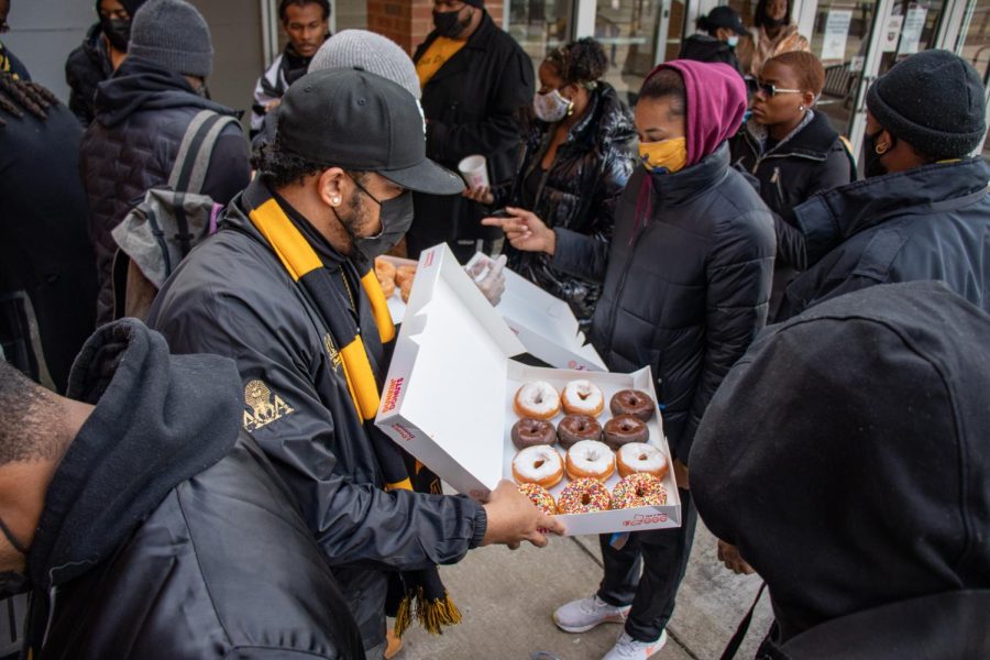 A member of the Alpha Phi Alpha Fraternity Inc. passes out donuts at the MLK Day March Jan. 17, 2022 at Grinnell Hall in Carbondale, Ill.
