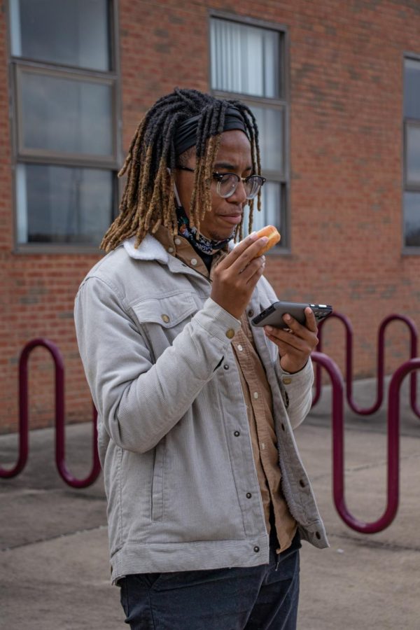 A participant in the Alpha Phi Alpha Fraternity Inc. MLK Day March eats a donut and looks at his phone before the march begins Jan. 17, 2022 in Carbondale, Ill. 