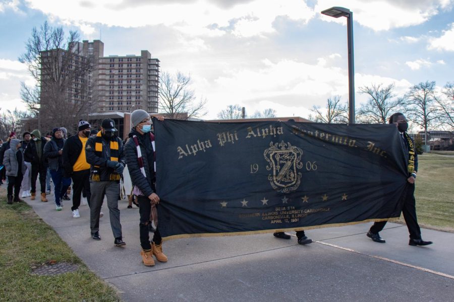 Alpha Phi Alpha Fraternity Inc. member, Jashaun Murray, and alumni member, Mathaniel Pierre, carry the fraternity banner during the MLK Day March Jan. 17, 2022 in Carbondale, Ill. 
