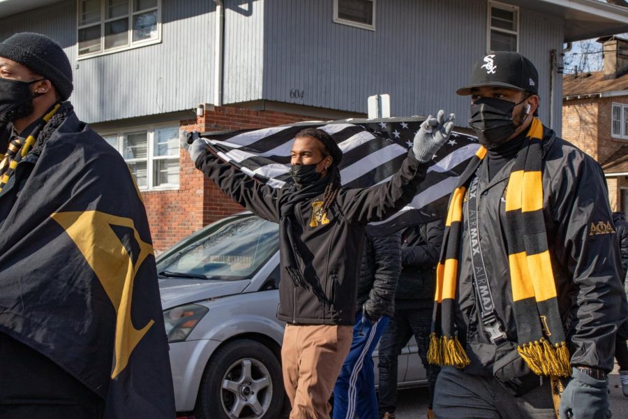 Alpha Phi Alpha Fraternity Inc. alumni Treyonne Rawls, holds a black and white American flag during the MLK Day March Jan. 17, 2022 in Carbondale, Ill. 