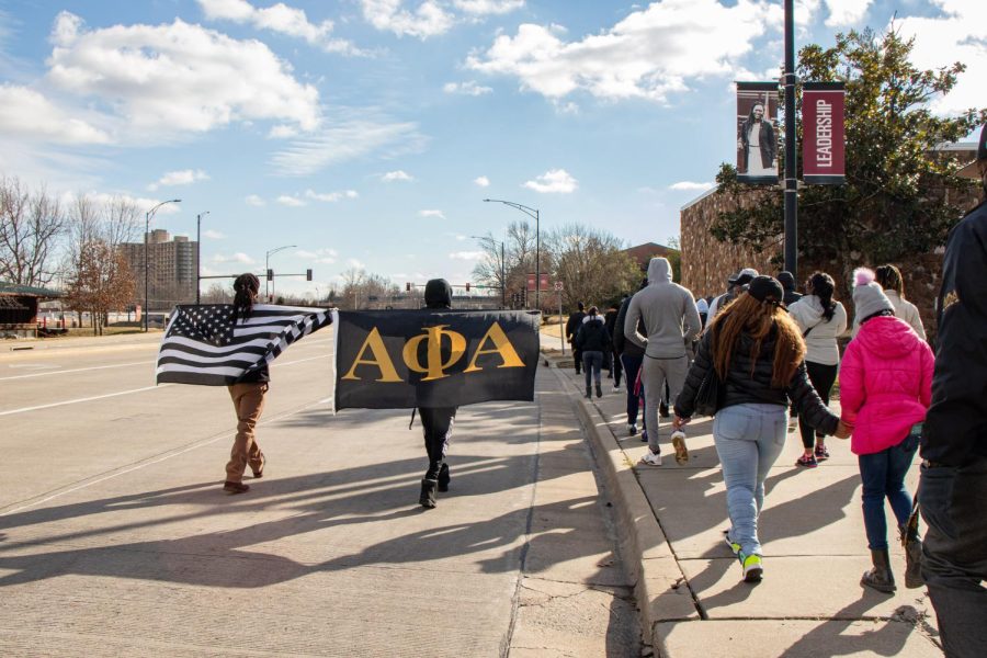 Participants in the Alpha Phi Alpha Fraternity Inc. MLK Day March carry a black and white American flag and the Alpha Phi Alpha flag as they walk down the street Jan. 17, 2022 in Carbondale, Ill. 
