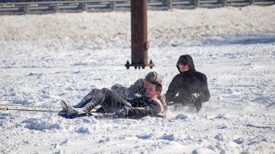 A group of sledders are pulled behind a car in a parking lot Feb. 4, 2022 in Carbondale, Ill. 