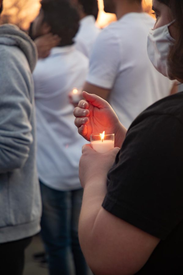 A student protects a candle from the wind during the vigil for SIU graduate students Vamshi Krishna Pechetty and Pavan Swarna April 22, 2022 at Becker Pavilion in Carbondale, Ill. 