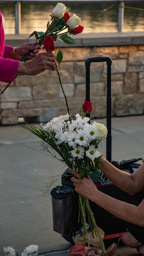 Women arrange flowers for the vigil in memory of SIU graduate students Vamshi Krishna Pechetty and Pavan Swarna April 22, 2022 at Becker Pavilion in Carbondale, Ill. 