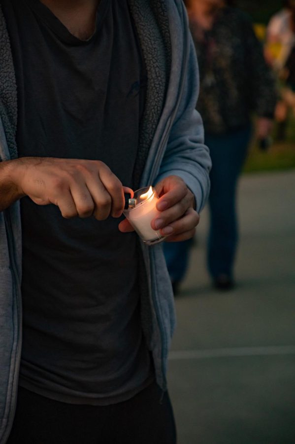 A man lights a candle in memory of SIU graduate students Vamshi Krishna Pechetty and Pavan Swarna April 22, 2022 at Becker Pavilion in Carbondale, Ill. 