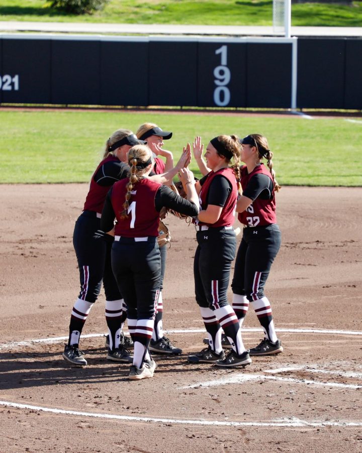 The+softball+team+high+fives+each+other+after+a+huddle+on+Wednesday%2C+April+6%2C+2022+at+Charlotte+West+Stadium+in+Carbondale%2C+Ill.%0A