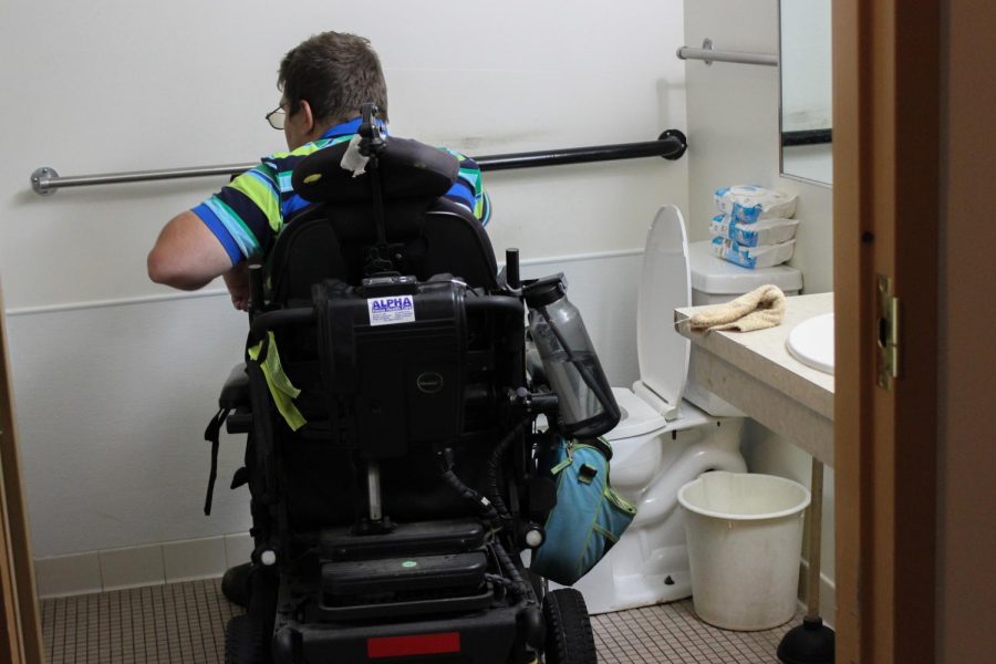 Dean Reece enters his accessible bathroom June 28, 2022 at Heartland Apartments in Carbondale, Ill. The bathroom is equipped with a wider doorway, handrails, and a larger shower. The bathroom is larger than most bathrooms so Reece is able to move around easier. 
