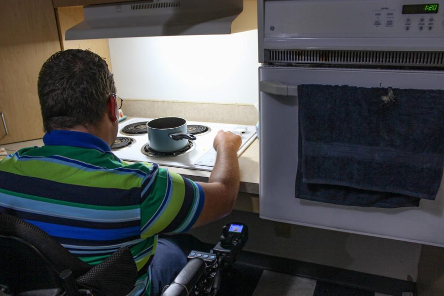 Dean Reece demonstrates how to use the wheelchair accessible stove June 28, 2022 at Heartland Apartments in Carbondale, Ill. The stove’s controls are located on the side of the burners so he is able to adjust the temperatures easier, rather than having to try and reach over the burners. There is also open space under the stove so his wheelchair can easily fit under. 