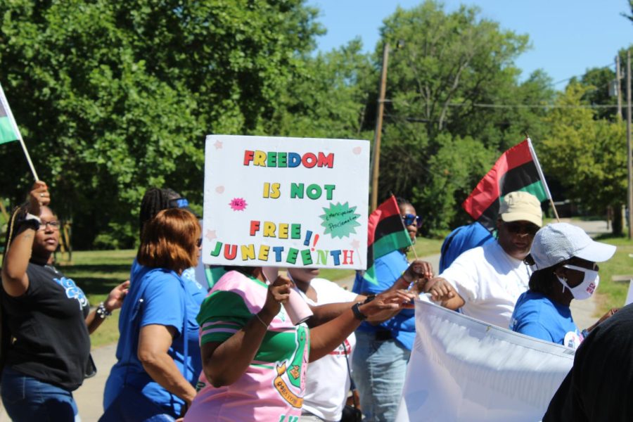 A participant holds a sing in the Juneteenth parade hosted by the African American Museum of Southern Illinois June 18, 2022 in Carbondale, Ill. 