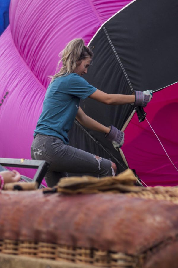 A woman holds open a hot air balloon as it is filled with air Aug. 20, 2022 at the Centralia Balloon Festival in Centralia, Ill.