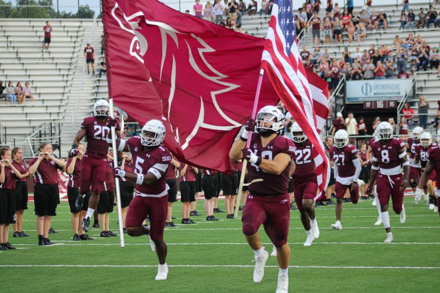 Chris Harris Jr. (5) and Jacob Garrett (43) leads the team onto the field through the tunnel, carrying the Saluki and American flag, kicking off the game against SEMO Redhawks for the War Of The Wheel  Sept. 10, 2022 at Saluki Stadium in Carbondale, Ill. 