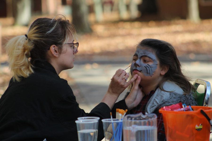 Serena Davis paints a childs face at The Haunted Hollow event Oct. 23, 2022 at Touch of Nature in Makanda, Ill. “I’ve been doing face painting for kids for a couple of years now and I really enjoy seeing their faces once it’s done,” Davis said. 