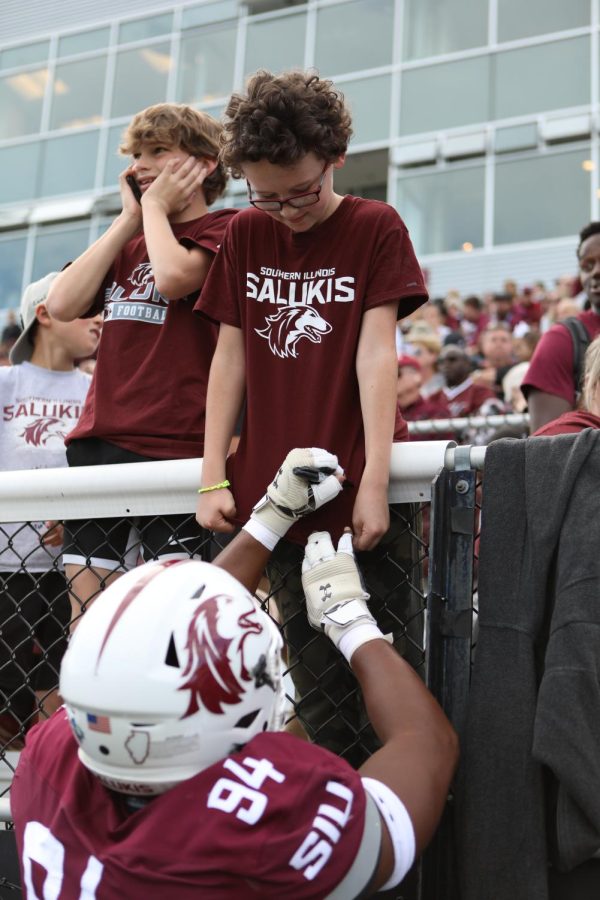 Quinton Lee (94) signs the t-shirt of Saluki fan Jax Hoeinghaus during halftime of the homecoming game Oct. 15, 2022 at Saluki Stadium in Carbondale, Ill.