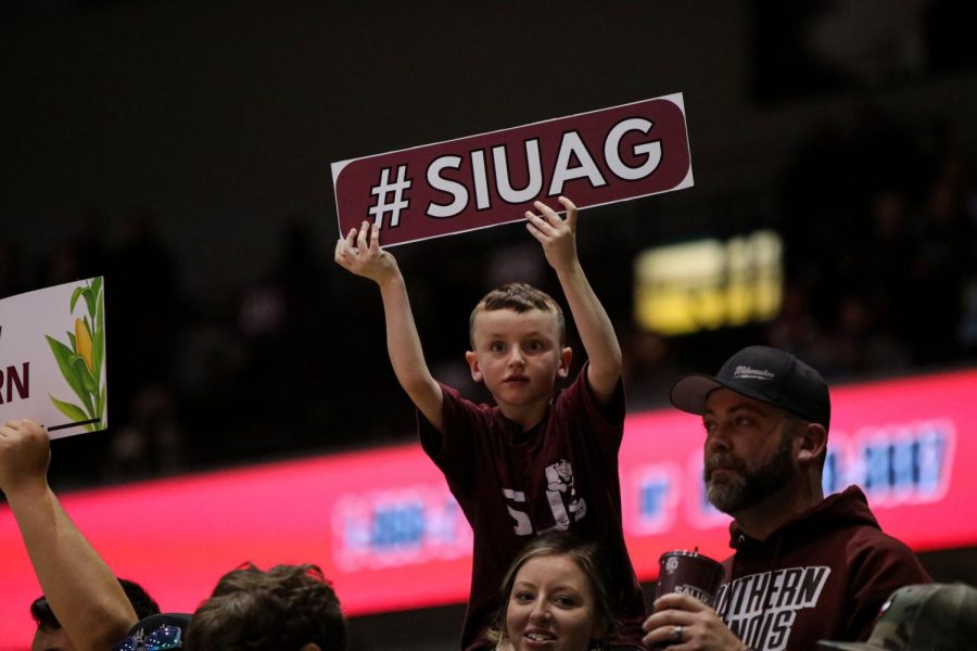 A young kid holds up a sign that reads #SIUAG when kids of all ages from local schools packed the stands in support of the Dawgs during the FFA Night Jan. 25, 2023 at Banterra Center in Carbondale, Ill.