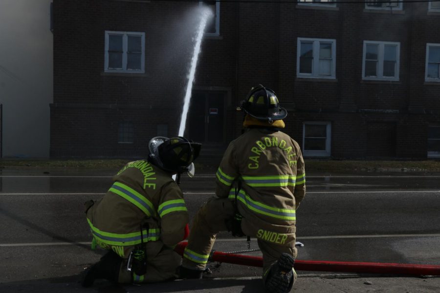 Firefighters Dan Snider and Jamison Bartlow man a hose aimed at Missionary Baptist Church as it burns on the corner of Walnut and S University Ave. Monday Feb. 6, 2023.