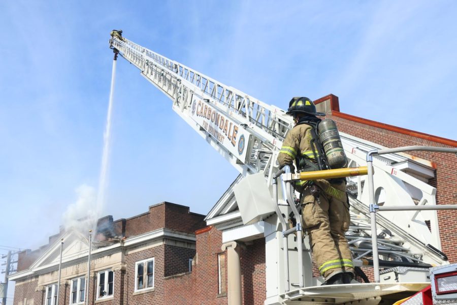 A firefighter stands at the foot of an aerial ladder while the fire at Missionary Baptist Church is extinguished in Carbondale, Monday Feb. 6, 2023.