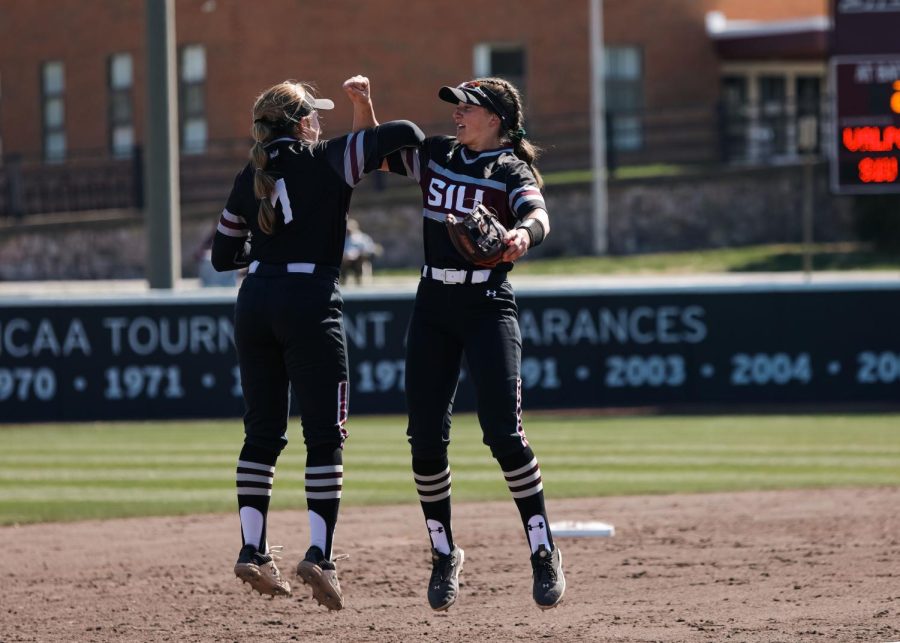 Rylie Hamilton (1) and Jackie Lis (00) share a handshake after they score the first two outs of the inning back to back against the Beacons of Valparaiso Mar. 19, 2023 at Charlotte West Stadium in Carbondale, Ill. 