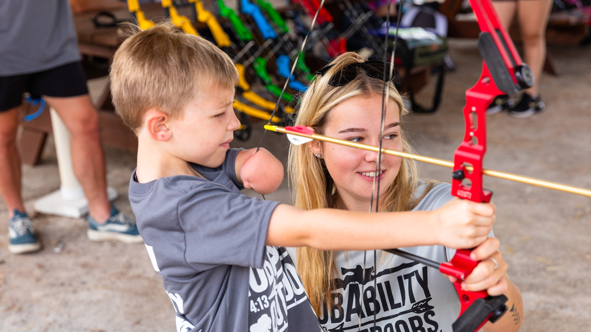SIU junior Blayke Spencer helps first-year participant Briggs Titus, 6, of Neoga, Illinois, with archery.