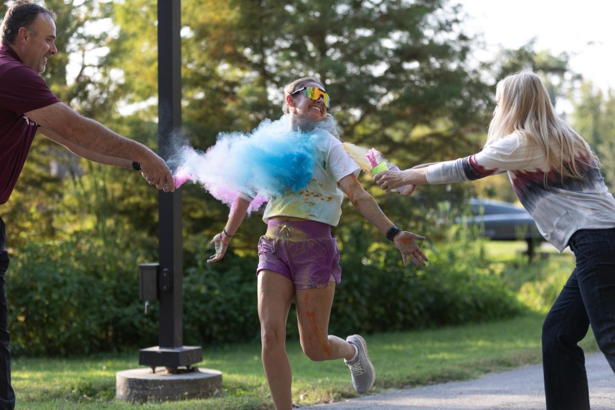 Jacqueline Crain is hit with a cloud of color after she crosses the finish line first at the third annual Color Fun Run hosted by the School of Health Sciences Sept. 29, 2023 at the Campus Lake in Carbondale, Illinois. 