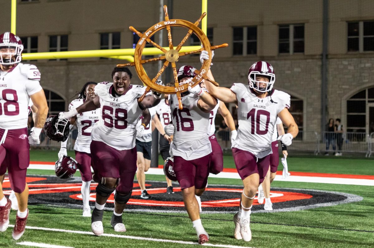 The Salukis run the newly claimed wheel back to the stands full of fans after the Dawgs beat out the Redhawks by one point Sept. 16, 2023 at Houck Stadium in Cape Girardeau, Missouri. Lylee Gibbs | @lyleegibbsphoto 