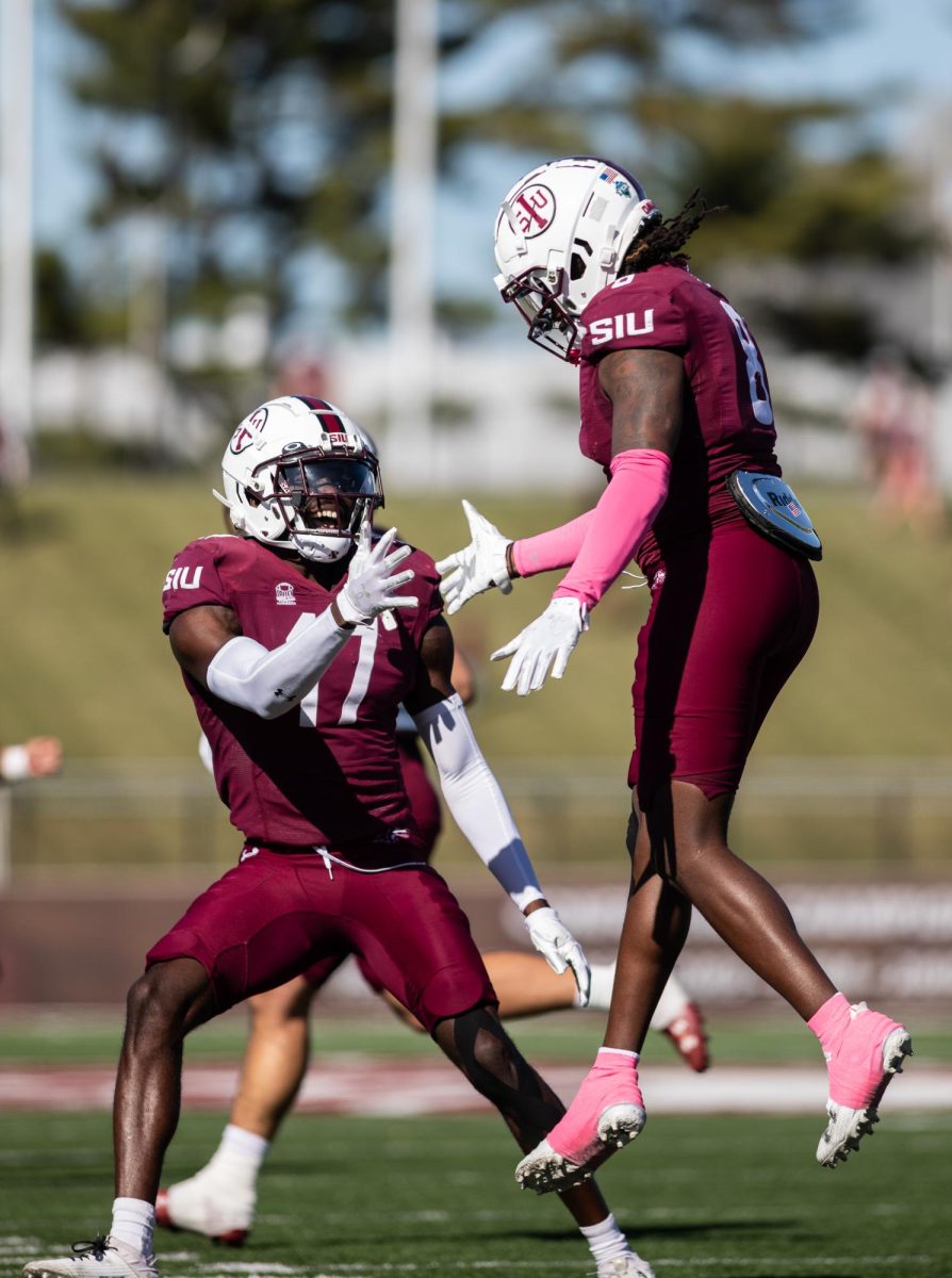 Dune Smith (8) jumps to high five Mark Davis Jr. (17) after taking down South Dakota State on defense Oct. 21, 2023 at Saluki Stadium in Carbondale, Illinois.