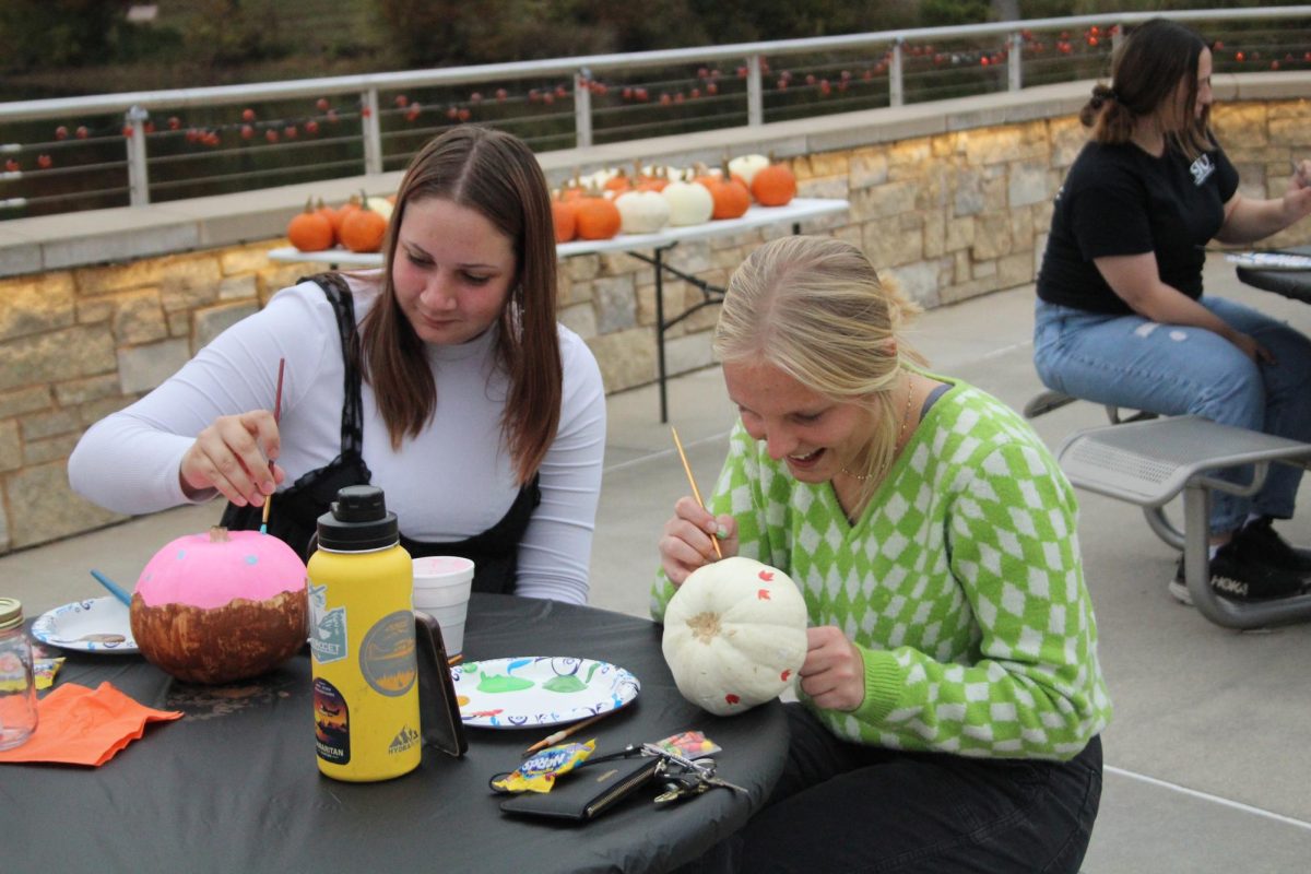 SIU Honors Assembly members Josie Boelter (right) and Delaney Redden paint pumpkins during Moonlight on the Lake hosted by SIU Honors Assembly Oct. 24, 2023 at Becker Pavilion in Carbondale, Illinois.