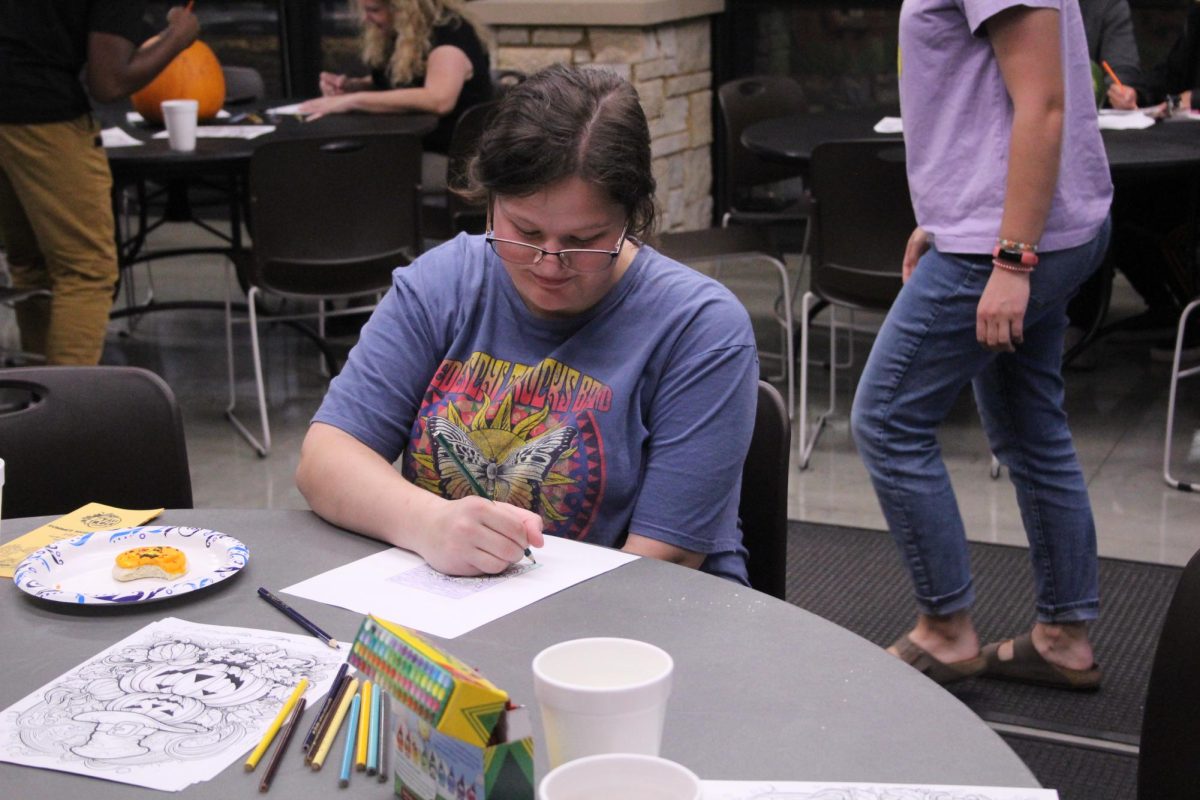 Rachel Hutchinson, zoology major, colors a spooky coloring sheet at Moonlight on the Lake hosted by SIU Honors Assembly Oct. 24, 2023 at Becker Pavilion in Carbondale, Illinois.