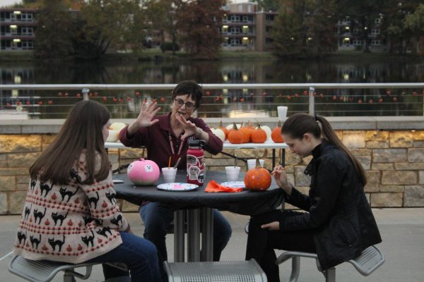 Brenda Sanders (middle) talks to freshman Iga Antoniak (right) and junior Katrina Stanley (left) as they paint pumpkins at Moonlight on the Lake Oct. 24, 2023 at Becker Pavilion in Carbondale, Illinois.