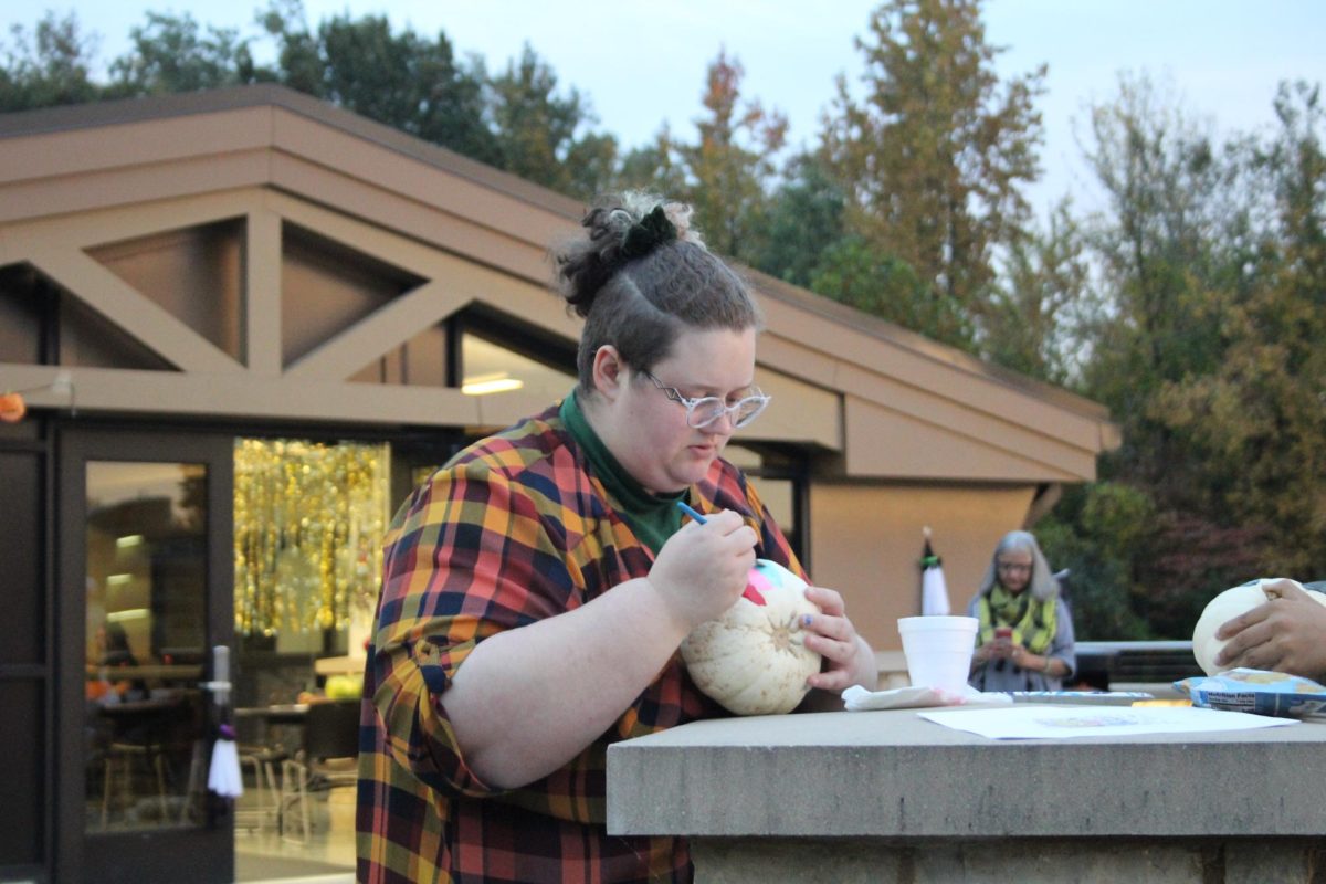 Dana Dolecheck paints a pumpkin during Moonlight on the Lake hosted by the SIU Honors Assembly Oct. 24, 2023 at Becker Pavilion in Carbondale, Illinois.