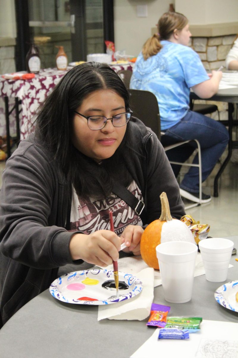 Yessenia Reyes paints her pumpkin white for Moonlight on the Lake Oct. 24, 2023 at Becker Pavilion in Carbondale, Illinois.