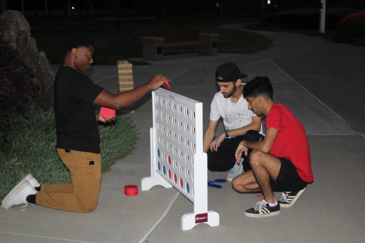 Saleh Alwadai (right), Duncan Hughes (left), Mansour Alzahrani (center) play Connect 4 Oct. 24, 2023 at Becker Pavilion in Carbondale, Illinois.
