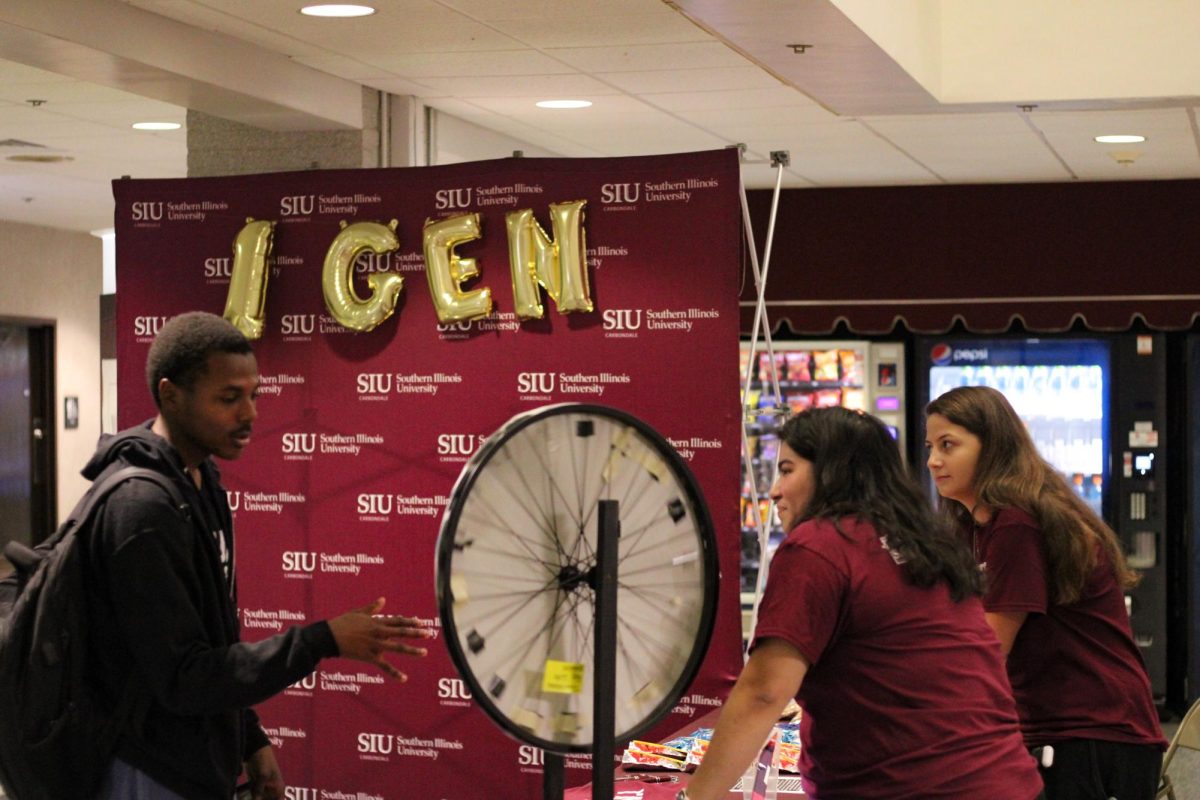 Keyshon Danzy (left) spins a wheel for a prize from Michelle Soto (middle) and Olivia Moscato (right) at the First-Gen College Celebration Kick Off Nov. 8, 2023 at SIU Student Center in Carbondale, Illinois.   