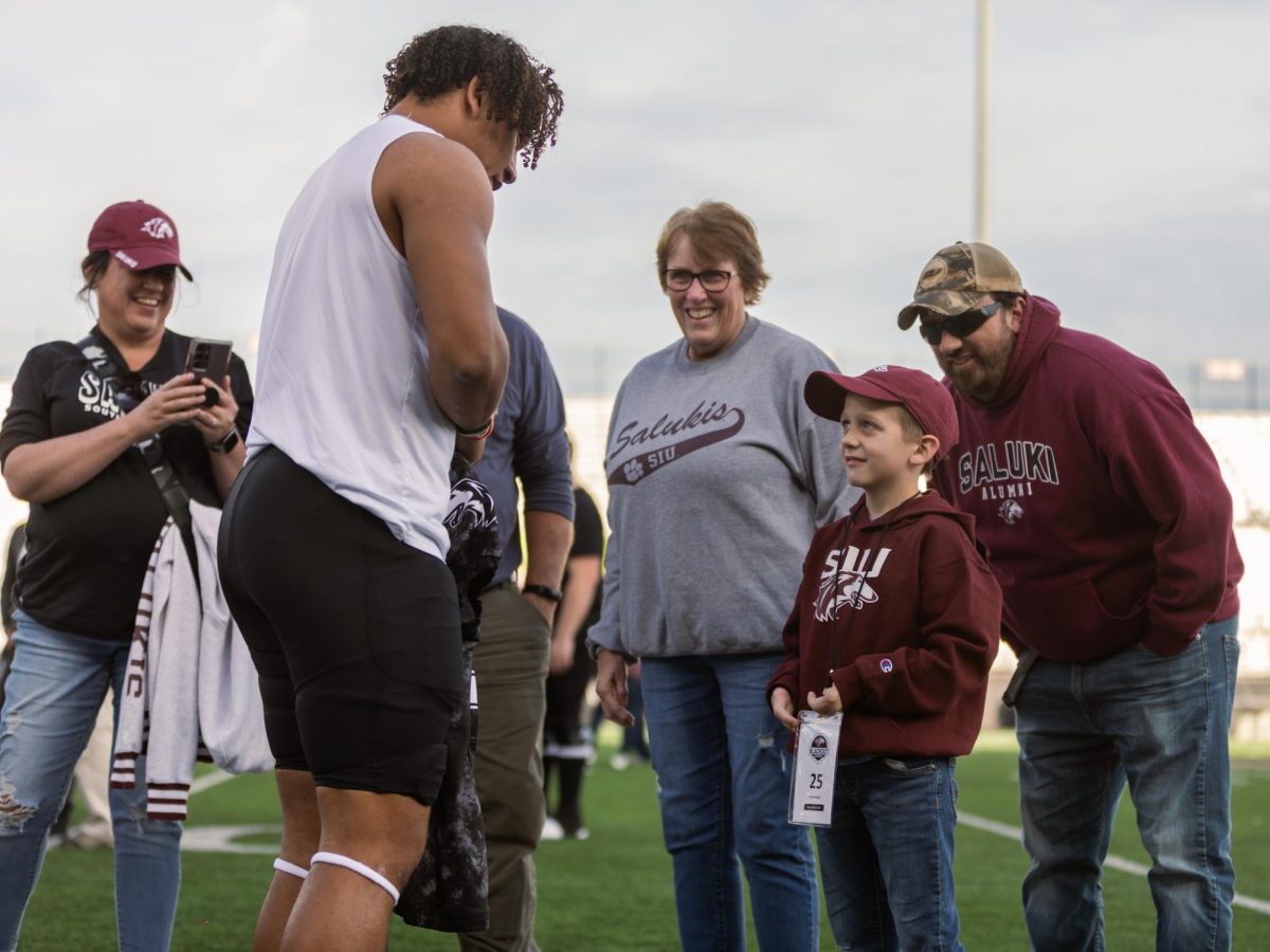 Kayleb Wagner hands off his game-worn jersey to young fan Hank moments after the end of the annual Blackout Cancer game Nov. 4, 2023 at Saluki Stadium in Carbondale, Illinois. 