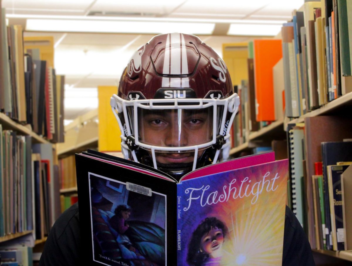 SIU safety Jeffery Wells (21) holds “Flashlight” by Betsy James and Stacey Schuett Nov. 8, 2023 at Morris Library in Carbondale, Illinois.