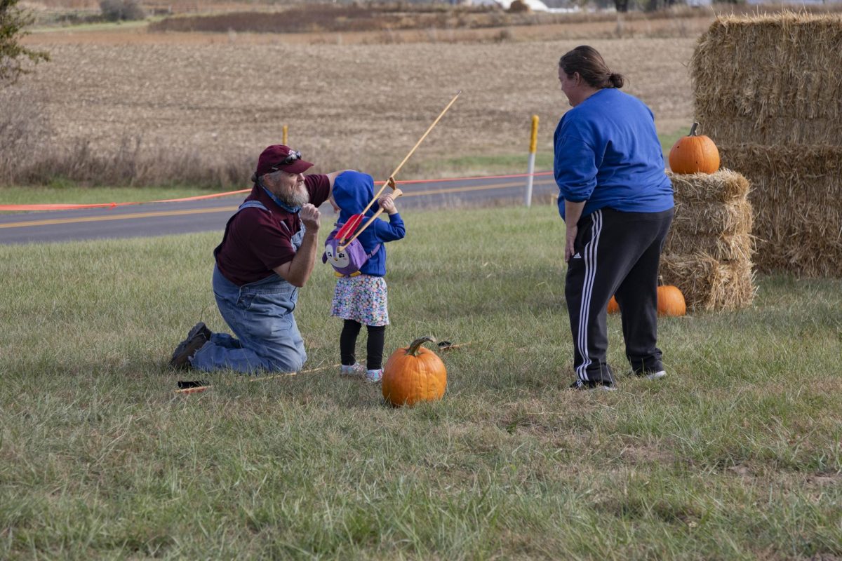 Erin Ashley (far right) watches as her daughter Amelia Ashely learns how to use an Atlatl Nov, 4. 2023 at The Great Southern Illinois Pumpkin Smash in Carbondale, Illinois. 
