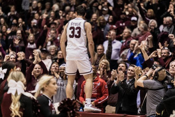 Jovan Stulic (33) stands on the scorer's table facing the crowd after the Salukis beat the Oklahoma State Cowboys Dec. 5, 2023 at Banterra Center in Carbondale, Illinois. 