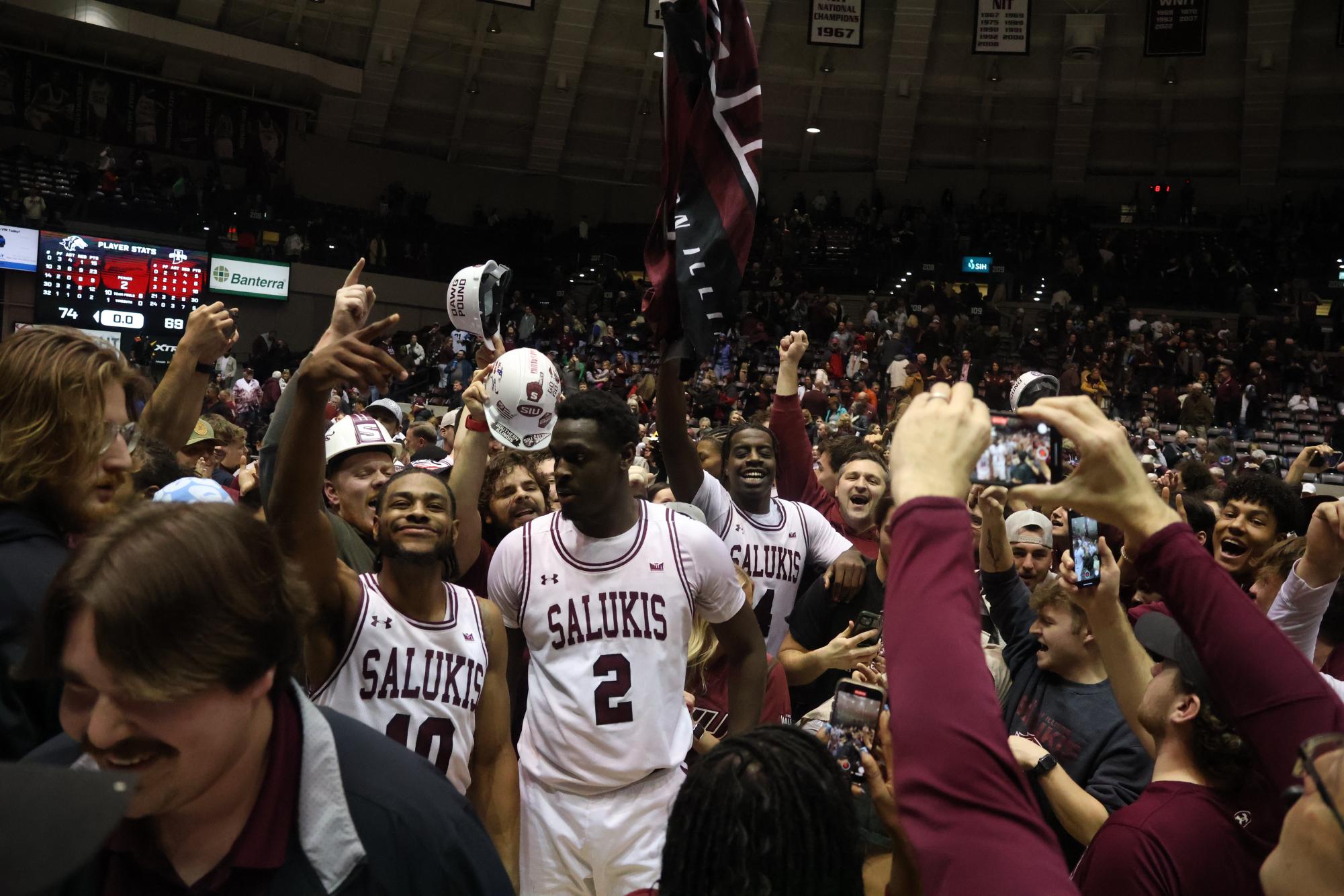 Clarence Rupert (4) waves the SIU flag in a crowd of Saluki players and fans as the Salukis take down No. 23 Indiana State at home Feb. 17, 2024 at Banterra Center in Carbondale, Illinois.