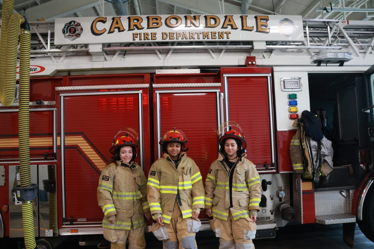 Katie Lipe (Left), Josephine Bailey (Center), Kulisara Lukes (Right) pose in front of the Carbondale, IL Fire Truck. March 20th, 2024
