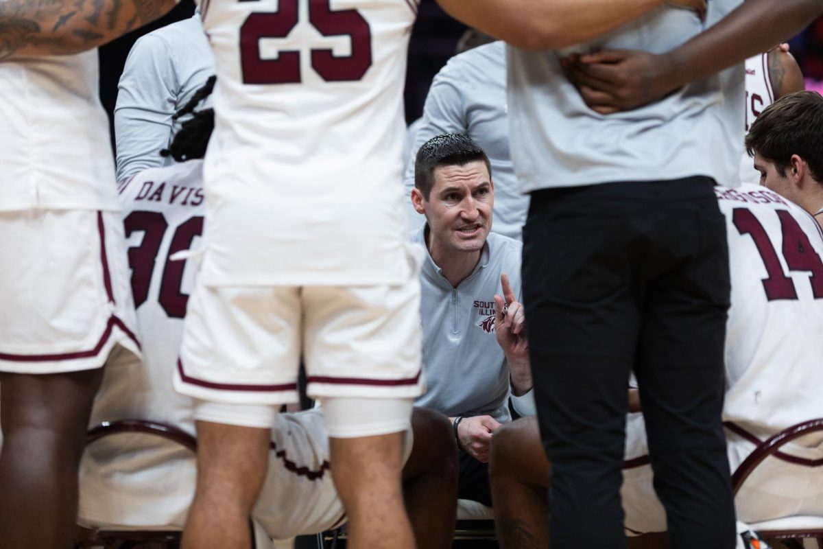 Head+Coach+Bryan+Mullins+speaks+with+Saluki+basketball+in+a+media+timeout+as+the+Salukis+face+the+Flames+of+UIC+March+7%2C+2024+at+Enterprise+Center+in+St.+Louis%2C+Missouri.+