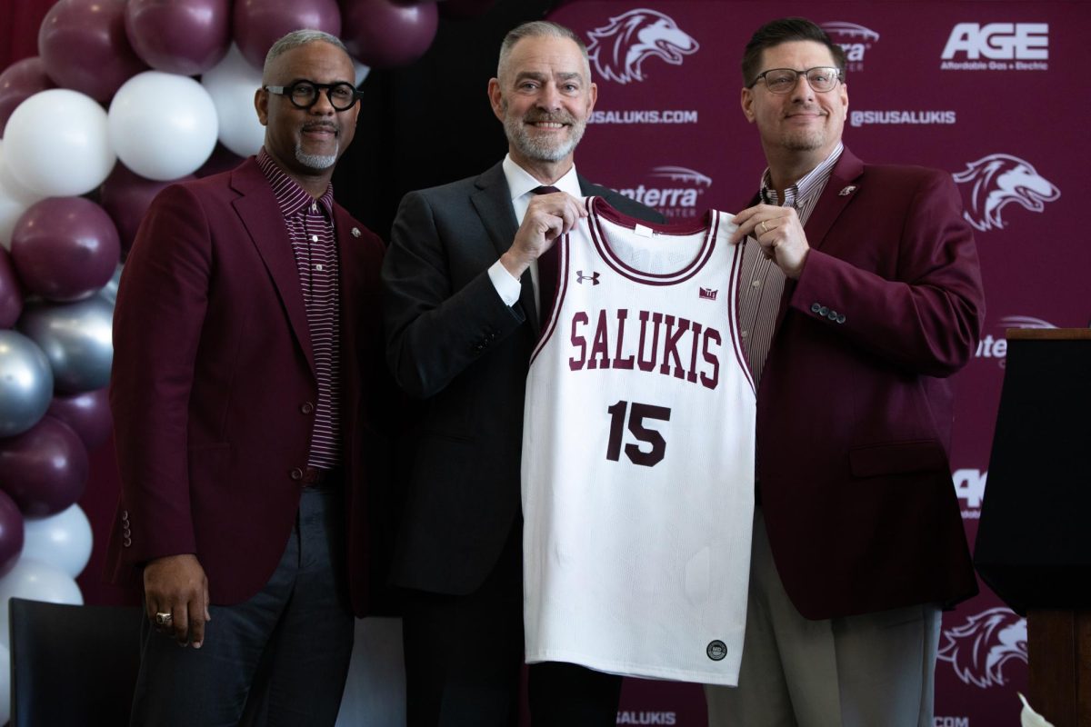 Basketball head coach Scott Nagy (middle) is presented a Saluki jersey by Athletic Director Tim Leonard (right) and Chancellor Austin Lane (left) in an introduction event March 29, 2024 at Charles Helleny Pavilion in Carbondale, Illinois.